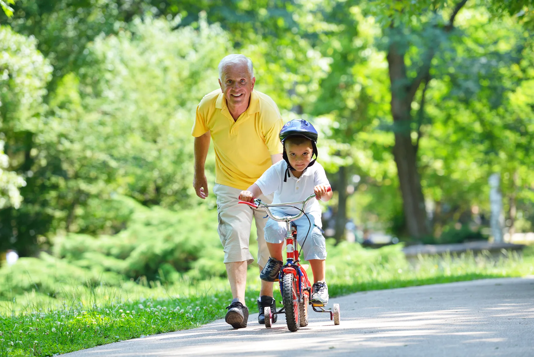 A man helping a child ride a bicycle outdoors